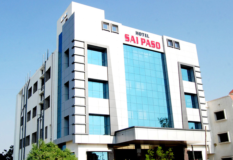 Front view of Hotel Sai Paso, a four-storey hotel with a glass facade in Shirdi